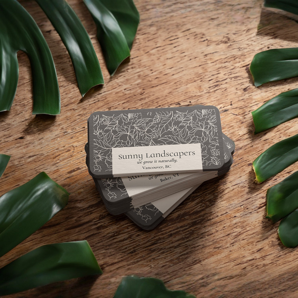 Bamboo paper business card samples on a wood surface with leaves