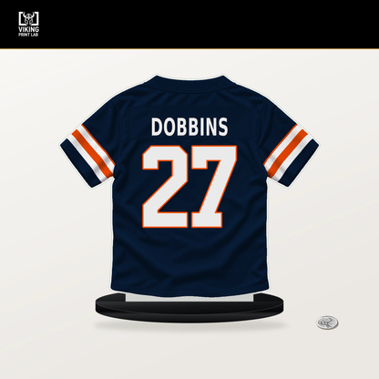 J.K. Dobbins number 27 Denver Broncos jersey stand with included black base.