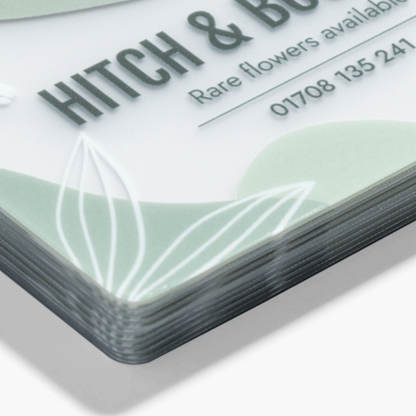 Close-up of a frosted plastic business card stack showing rounded corners, the material edge and an example design.